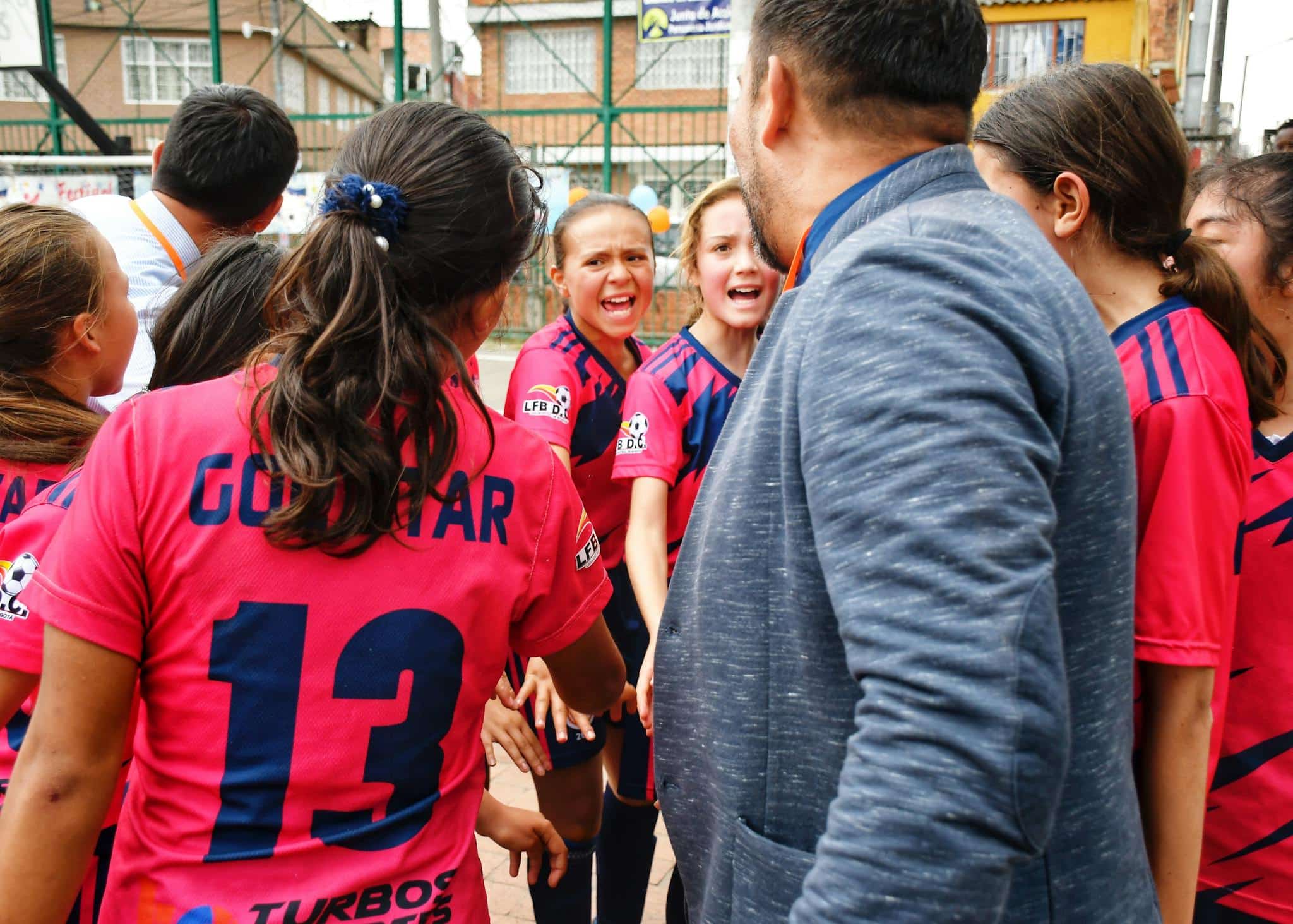 A vibrant moment capturing a youth soccer team in a motivational huddle with their coach, outdoors.
