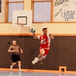 Action shot of a handball player jumping in an indoor sports arena in France.