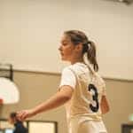 Teen girl in action on an indoor basketball court, focused and ready to play.