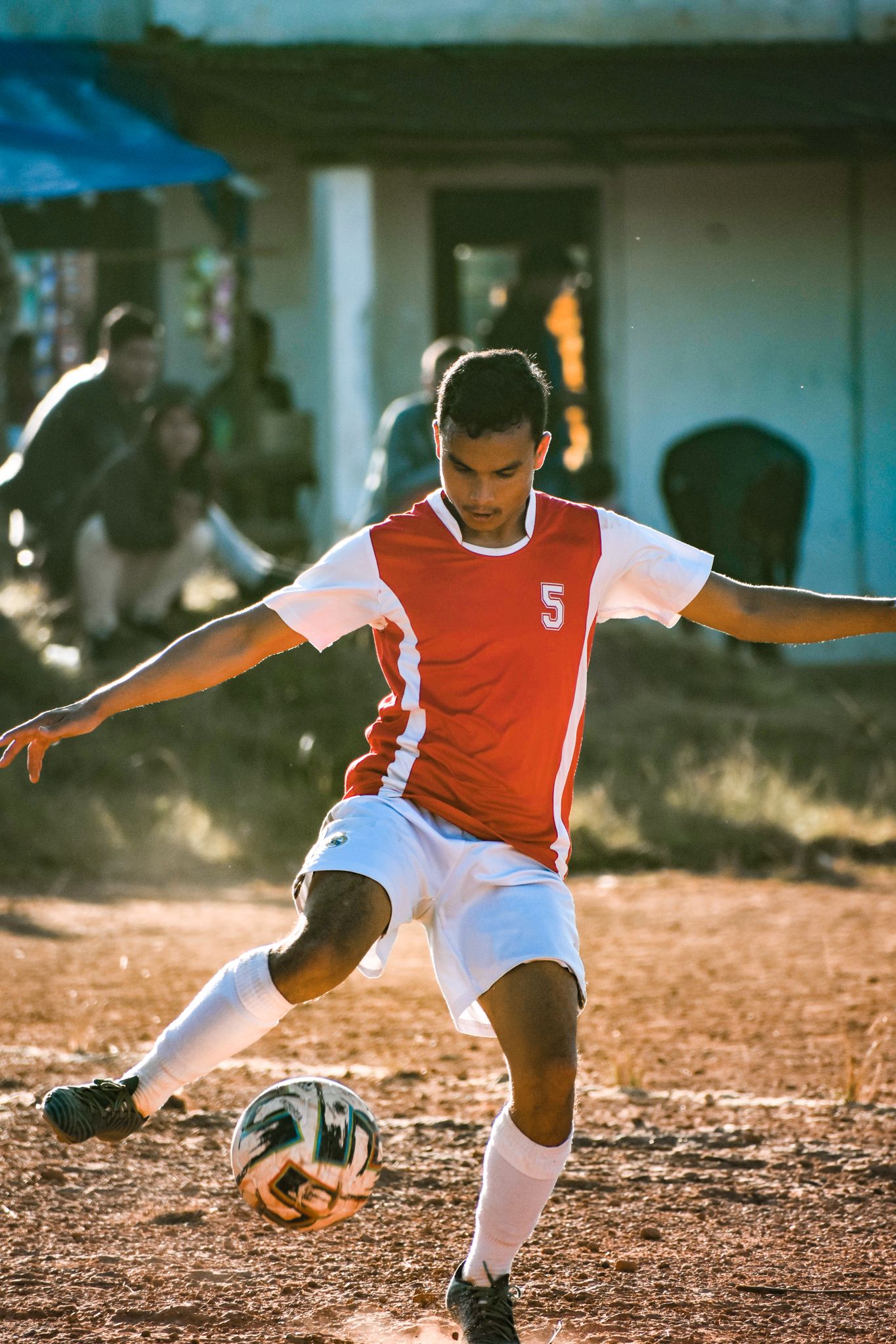 A young man playing soccer outdoors on a sunny day, showing dynamic movement.