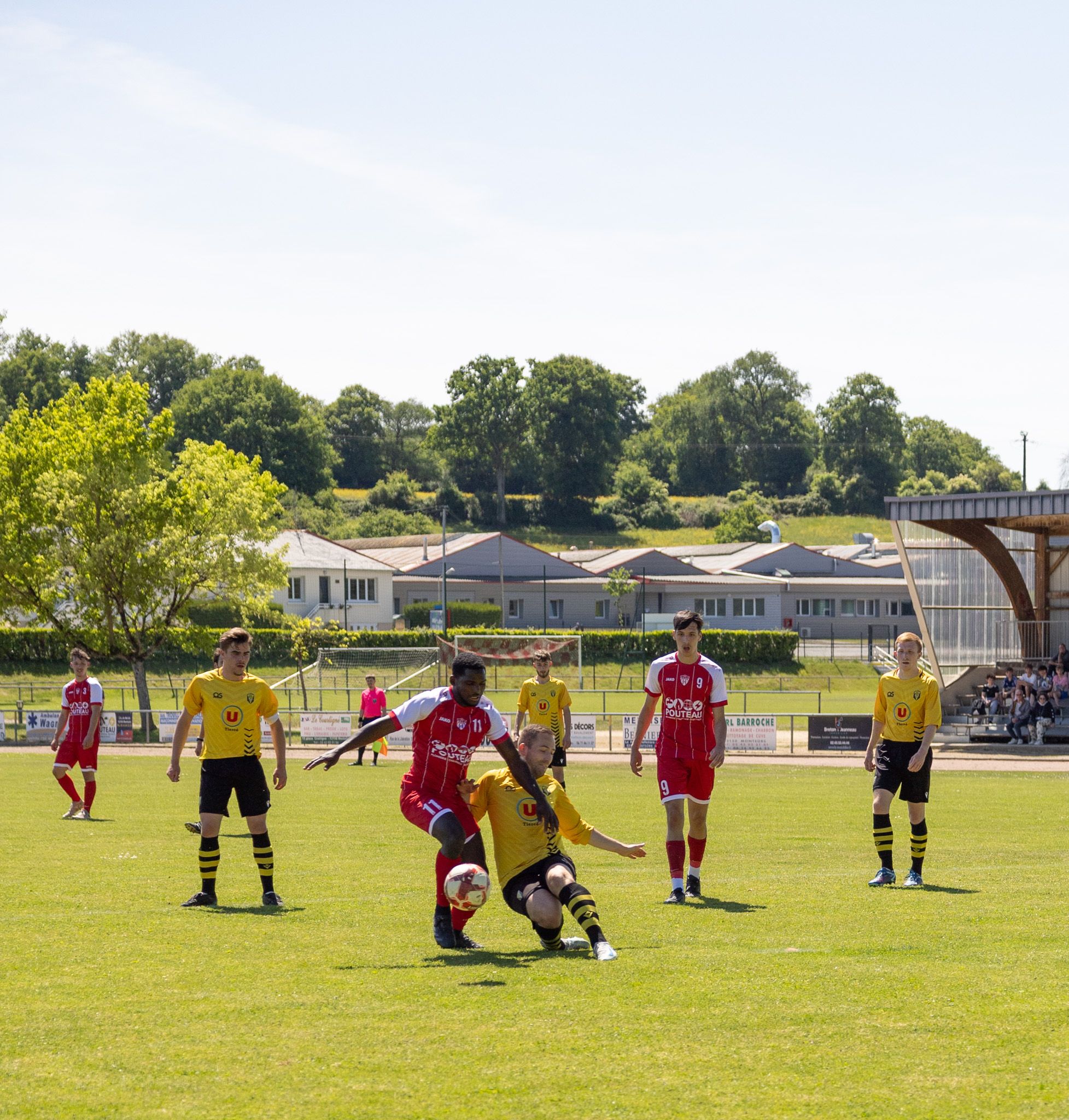 Dynamic football action captured during an outdoor match in France under clear skies.