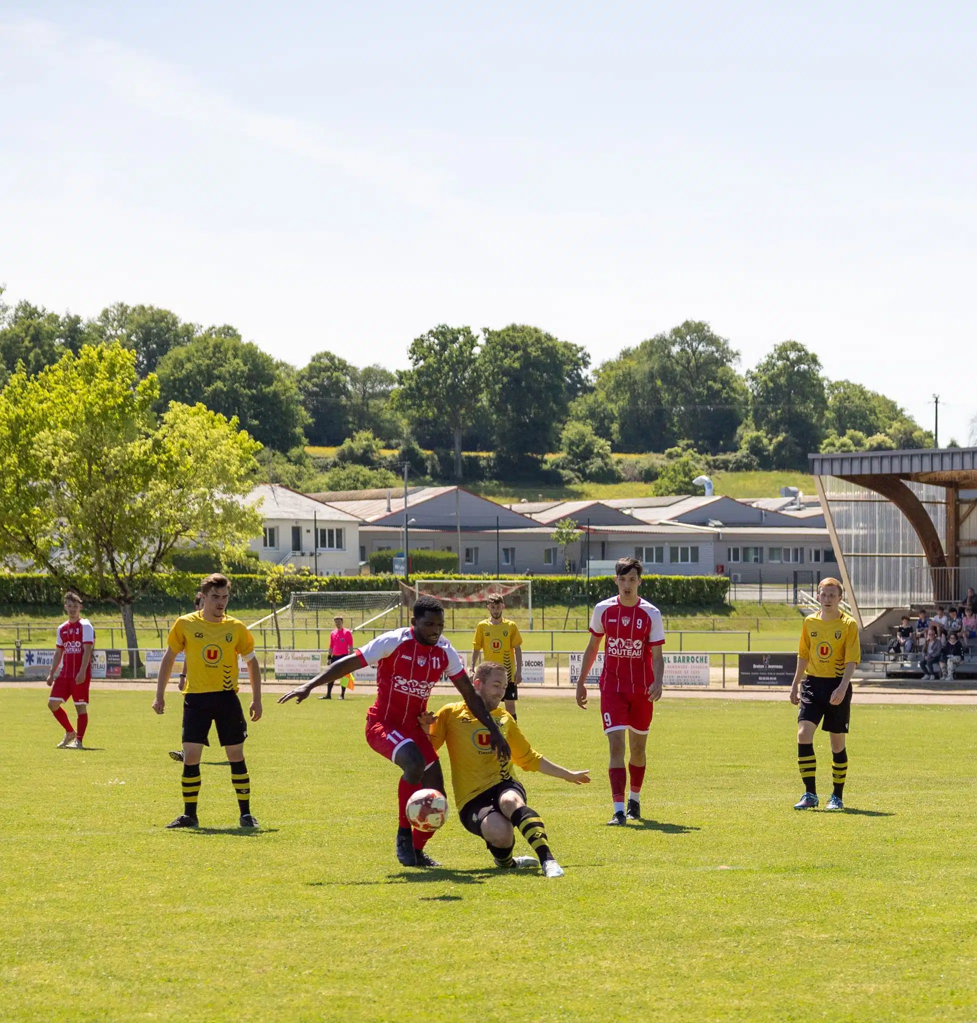 Dynamic football action captured during an outdoor match in France under clear skies.