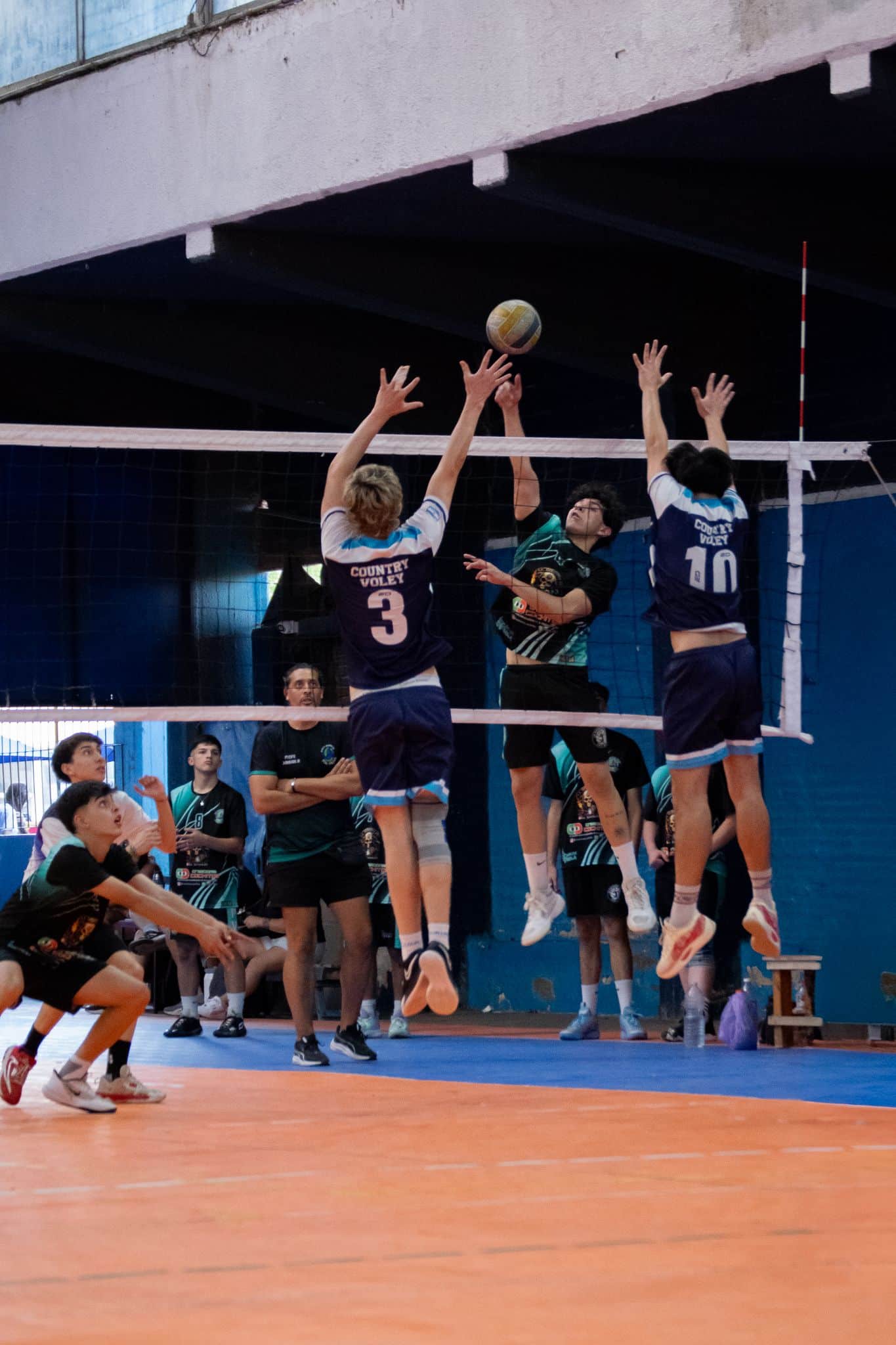 High school volleyball players in action during a competitive indoor match.