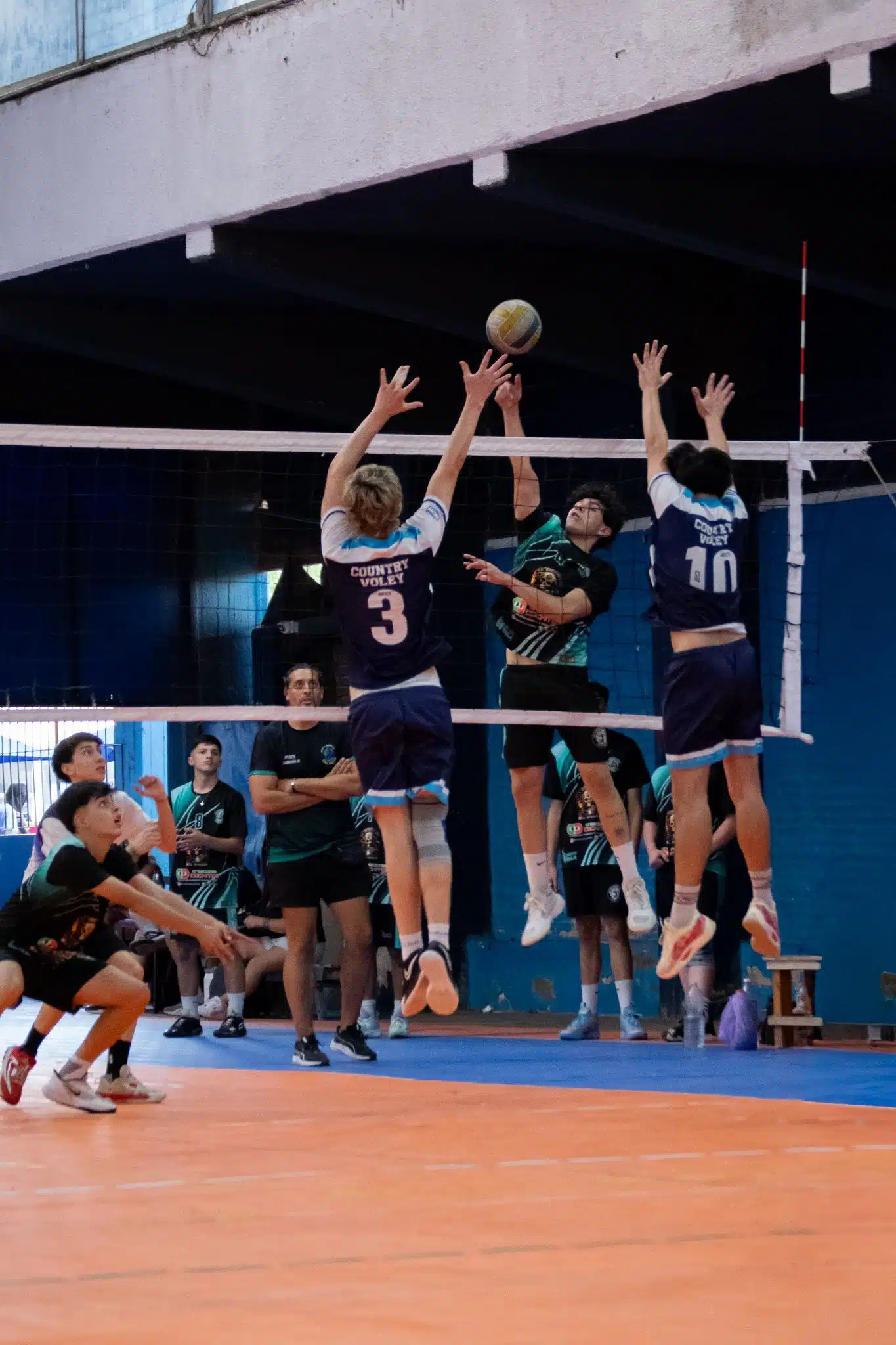 High school volleyball players in action during a competitive indoor match.