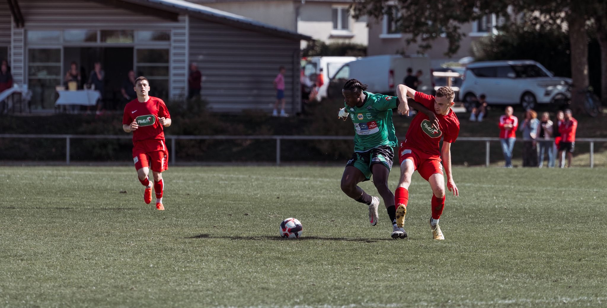Players in action during an outdoor soccer match on a sunny day in France.