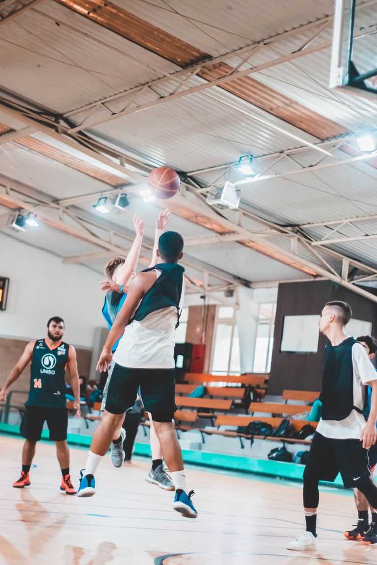 Young athletes playing basketball indoors showcasing teamwork and sport dynamics.